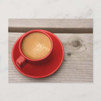 A bright red cup of espresso coffee on a picnic postcard