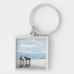 A couple riding horses on Parkiri beach in New Keychain