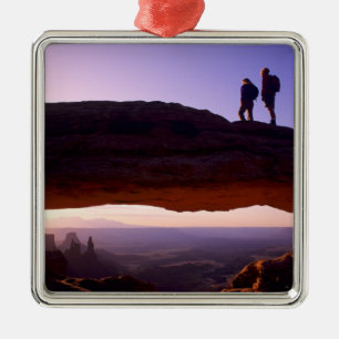 A couple watches sunrise from atop Mesa Arch in Metal Ornament