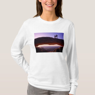 A couple watches sunrise from atop Mesa Arch in T-Shirt