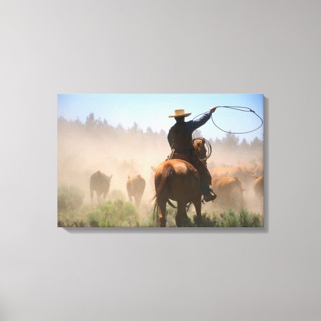 A cowboy out working the herd on a cattle canvas print (Front)