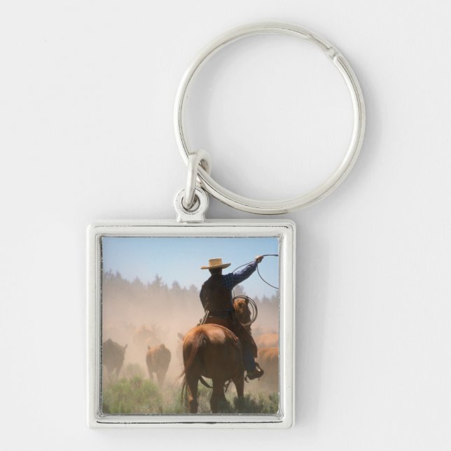 A cowboy out working the herd on a cattle keychain (Front)