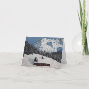 A cozy winter cottage, snowy mountains and forest holiday card
