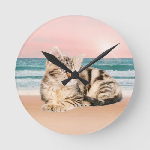 A Cuter Striped Cat Sitting on Beach with sunset Round Clock