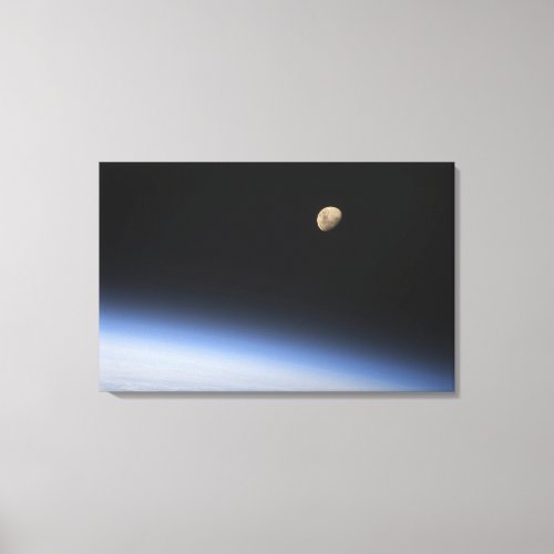 A gibbous moon visible above Earths atmosphere 2 Canvas Print