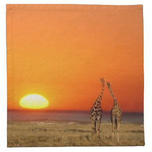 A Giraffe couple walks into the sunset, in Napkin