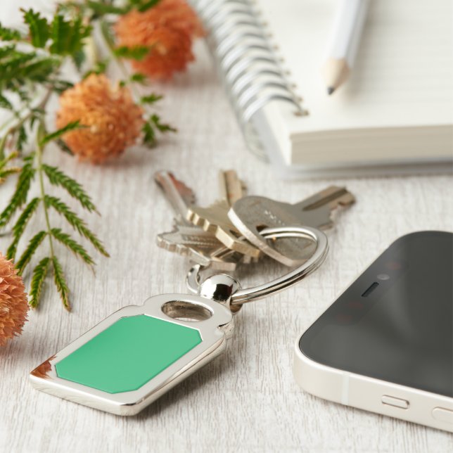 a green background with a white border keychain (Side)