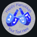 A Hanukkah Dreidels In Blue Cheerful Kids Design Classic Round Sticker<br><div class="desc">Use these fun round Hanukkah stickers as party favors, to dress up a gift package, to seal envelopes or anything else your DIY self can imagine. The double Dreidel design in white and bright blues is my original artwork so these Chanukah stickers are one-of-a-kind. Set on a faux bling silver...</div>