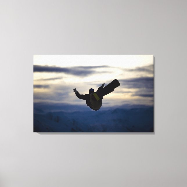 A male snowboarder does a back flip while riding canvas print (Front)