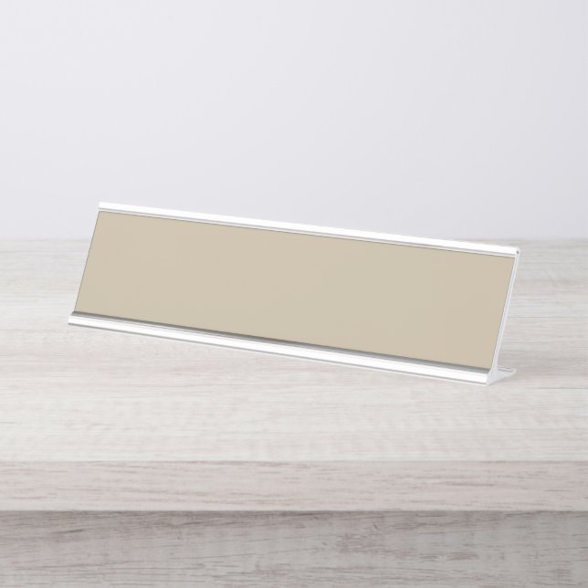 a man in a suit and tie standing in front of a wal desk name plate (Front)