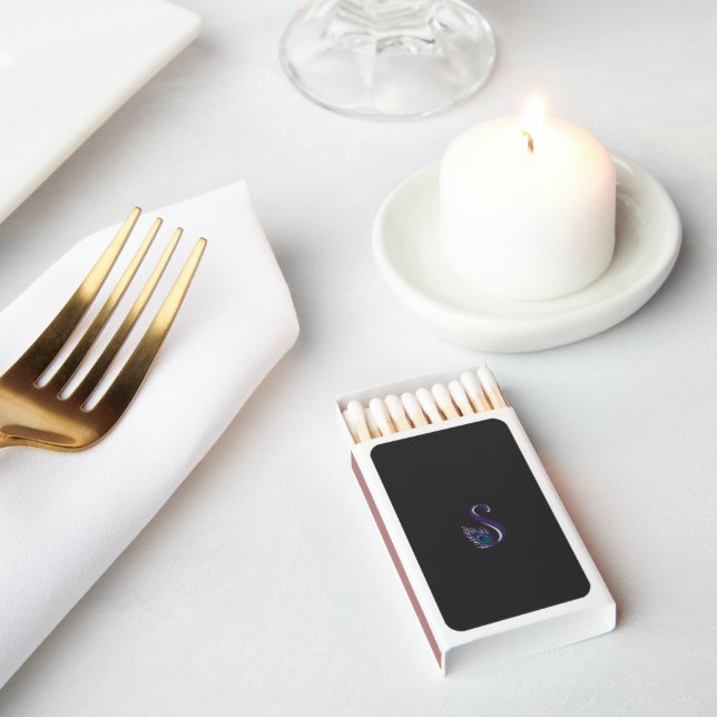 a purple and green peacock feather on a black back matchboxes (Insitu)