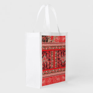 a red and green floral design on a black backgroun grocery bag