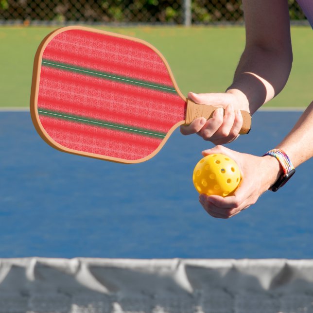 a red and green striped background carbon fiber pickleball paddle  (Insitu)