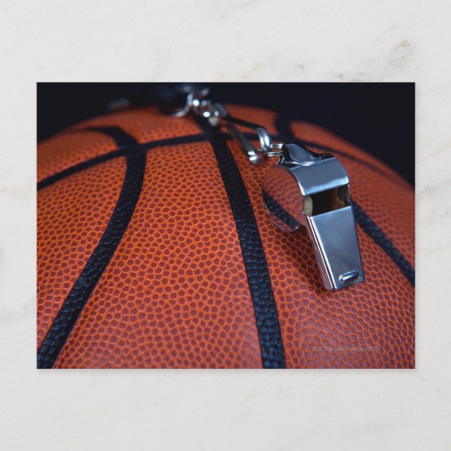 A referee's whistle rests on top of a postcard (Front)