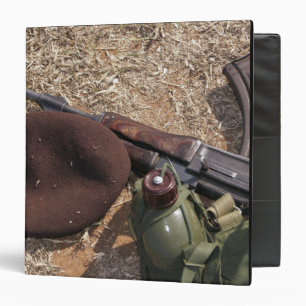 A rifle, military cover and canteen 3 ring binder