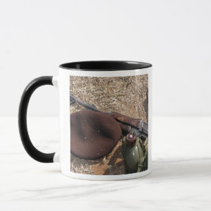A rifle, military cover and canteen mug