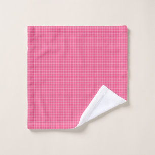 A set of pink gingham-patterned bath linens hangs 