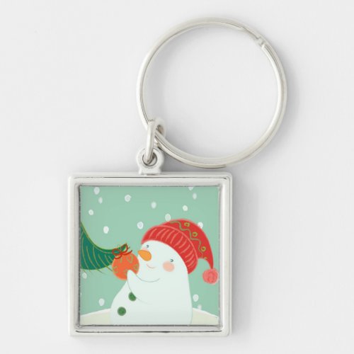 A snowman hanging an ornament on a tree keychain