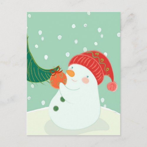 A snowman hanging an ornament on a tree postcard