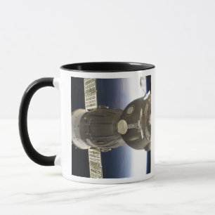 A Soyuz spacecraft backdropped by Earth Mug
