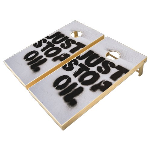 A spray painted sign that says just stop oil cornhole set