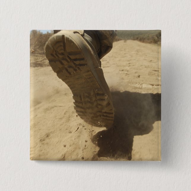 A US soldier walks along a dirt path Button (Front)
