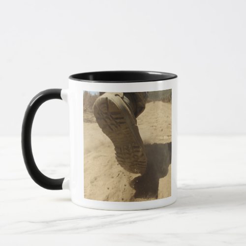 A US soldier walks along a dirt path Mug