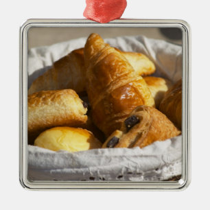 A wicker breakfast basket with croissants, and metal ornament