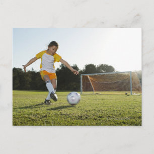 A young girl playing soccer on a soccer field in postcard