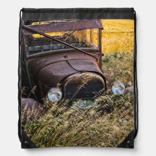 Abandoned old car in tall grass drawstring bag