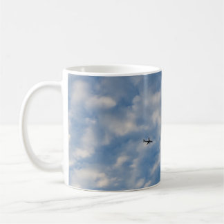 Airplane Crossing a Cloud-Filled Blue Sky Coffee Mug