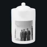 America President John Kennedy & Brothers, Camelot Teapot<br><div class="desc">The sun beat down on the three Kennedy brothers as they stood beneath the familiar white portico of the White House. President John F. Kennedy, the eldest, leaned against a pillar, a wry smile playing on his lips. His younger brothers, Robert and Ted, stood beside him, their faces a mix...</div>