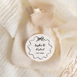 Amour | Illustrated French Bow Wedding Classic Round Sticker<br><div class="desc">This chic and elegant wedding favor sticker features a hand drawn,  wavy illustrated frame with a bow,  and stylish handwritten script for a Parisian or French style wedding invitation. This classic color option is ivory and black.</div>