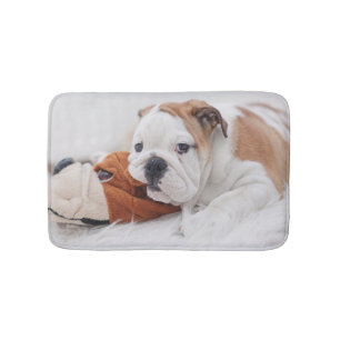 An English Bulldog Puppy Playing With A Bulldog Bathroom Mat
