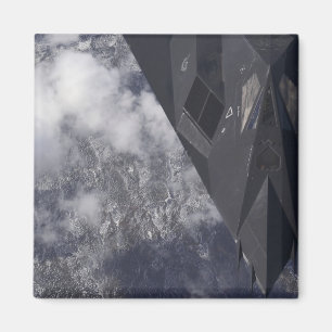 An F-117A Nighthawk flies high over the mountai Magnet