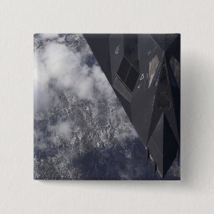 An F-117A Nighthawk flies high over the mountai Pinback Button