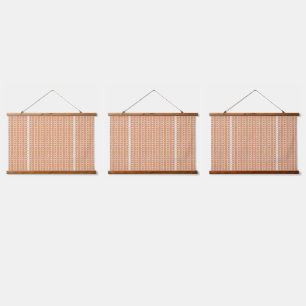 An orange rug with a textured pattern lies flat on hanging tapestry