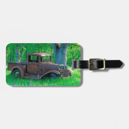 Antique rusted truck in a meadow luggage tag