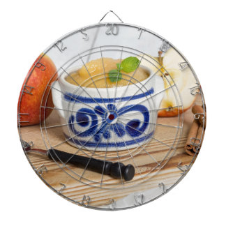 Applesauce with cinnamon in stoneware bowl dartboard with darts