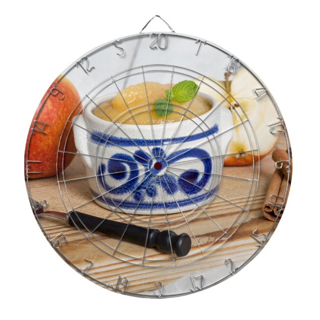 Applesauce with cinnamon in stoneware bowl dartboard with darts (Front)