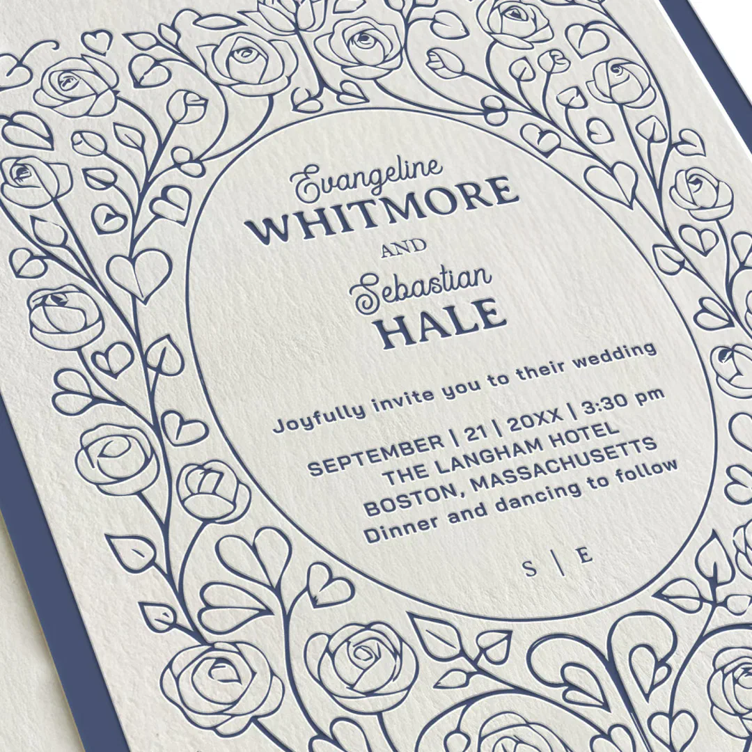 An enhanced/zoomed image of the invitation that has navy text and a rose and petal intricate design.