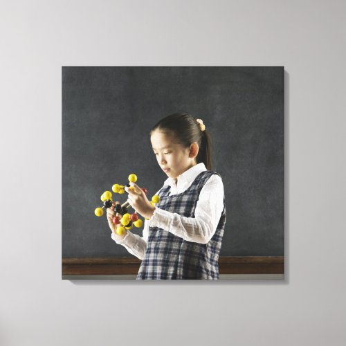 Asian girl looking at molecule model canvas print