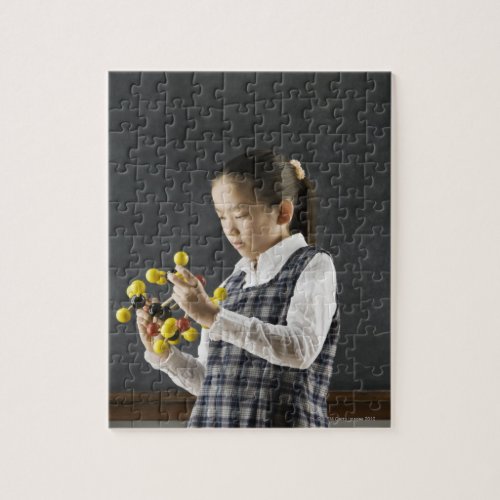 Asian girl looking at molecule model jigsaw puzzle