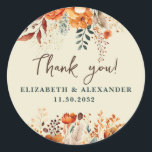 Autumnal names and wedding date floral thank you classic round sticker<br><div class="desc">These romantic and elegant autumnal floral Thank-you stickers make the perfect seal for your wedding favor, presenting a chic botanical design that features a classy watercolor illustration of flowers and greenery in warm fall tones and is easily customizable with your names and wedding date. These stickers are part of the...</div>