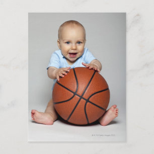 Baby boy (6-9 months) holding basketball, postcard