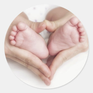 Baby feet in mother hands classic round sticker