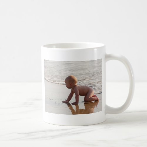 Baby playing in the sand on the beach coffee mug