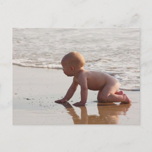Baby playing in the sand on the beach postcard