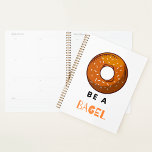 Be a Bagel Funny Food Pun Bagel Lover Design  Planner<br><div class="desc">Stay organized with a touch of humor using this “Be a Bagel” spiral planner. Featuring a fun bagel illustration and a witty pun, this planner is perfect for food lovers, brunch enthusiasts, and anyone who enjoys quirky designs. With a durable spiral binding and high-quality pages, it’s ideal for keeping track...</div>