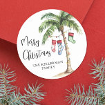 Beach Christmas Classic Round Sticker<br><div class="desc">Get into the holiday spirit with this festive watercolor Christmas sticker featuring a large palm tree wrapped in colorful Christmas lights. Three holiday stockings hang playfully from the fronds, with soft beach sand at the base for a warm, tropical touch. The hand-painted look adds charm and personality, while the mix...</div>